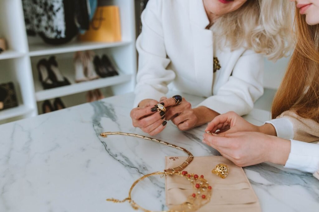 Two women examining luxury jewelry on a marble table in a boutique.